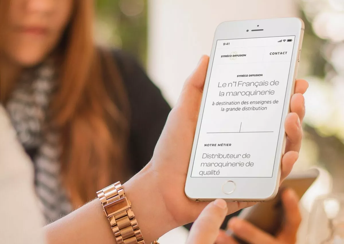 Main utilisant un smartphone affichant le site web de Syfreco distribution